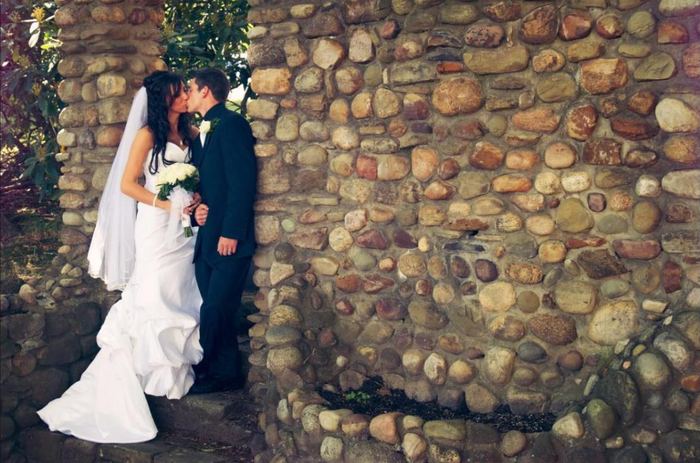 Couple kissing beside a river-rock wall
