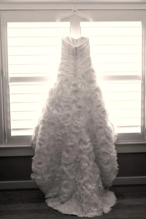 Wedding gown hanging in a sunlit window