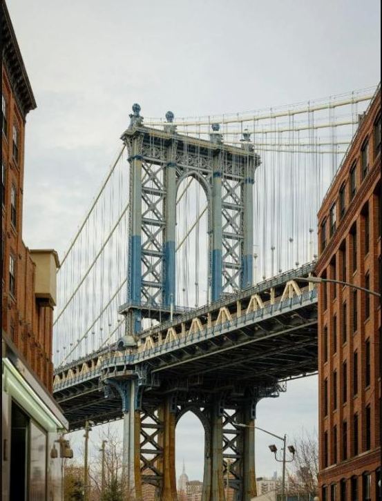 The Manhattan Bridge framed between brick buildings