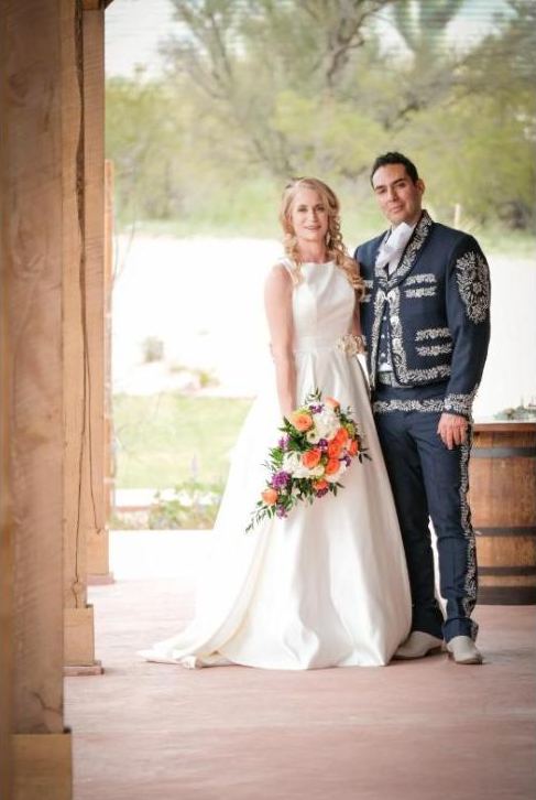 Bride and groom standing beneath a wooden porch